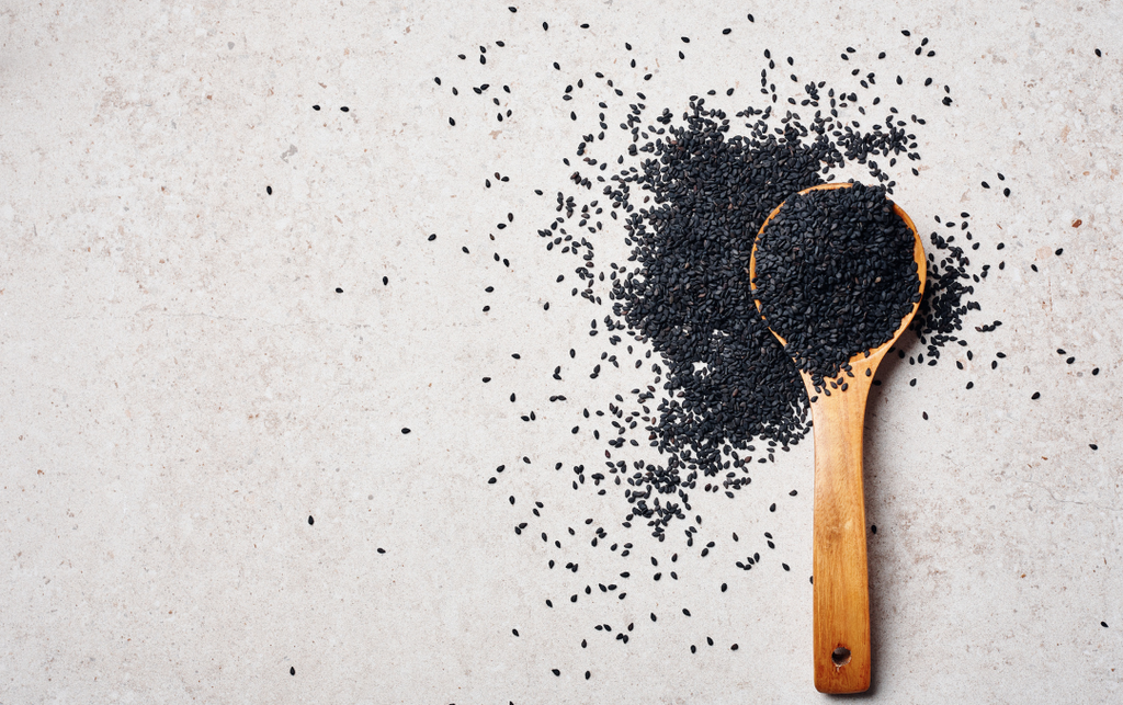 Black cumin seed oil and a spoonful of black seeds, known for their healing properties against acne