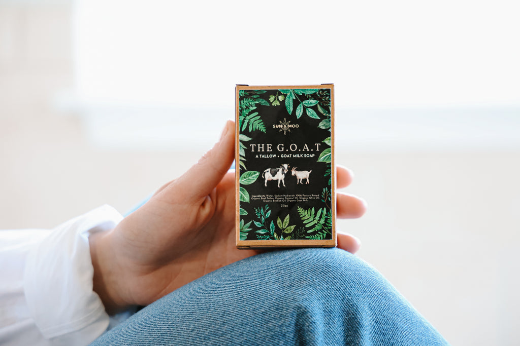 A close-up of a hand holding a bar of all-natural tallow and goat milk soap, showcasing its creamy texture and gentle formula, ideal for nourishing and cleansing the skin.