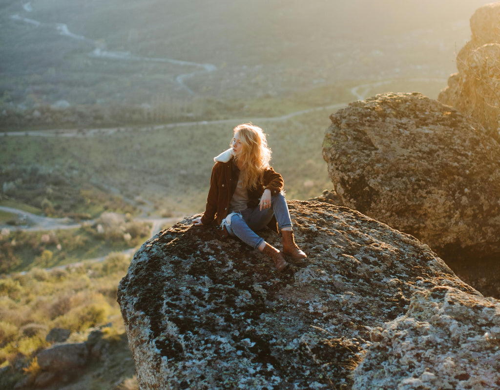 A woman with her eyes closed, surrounded by natural elements symbolizing self-care and menstrual health.